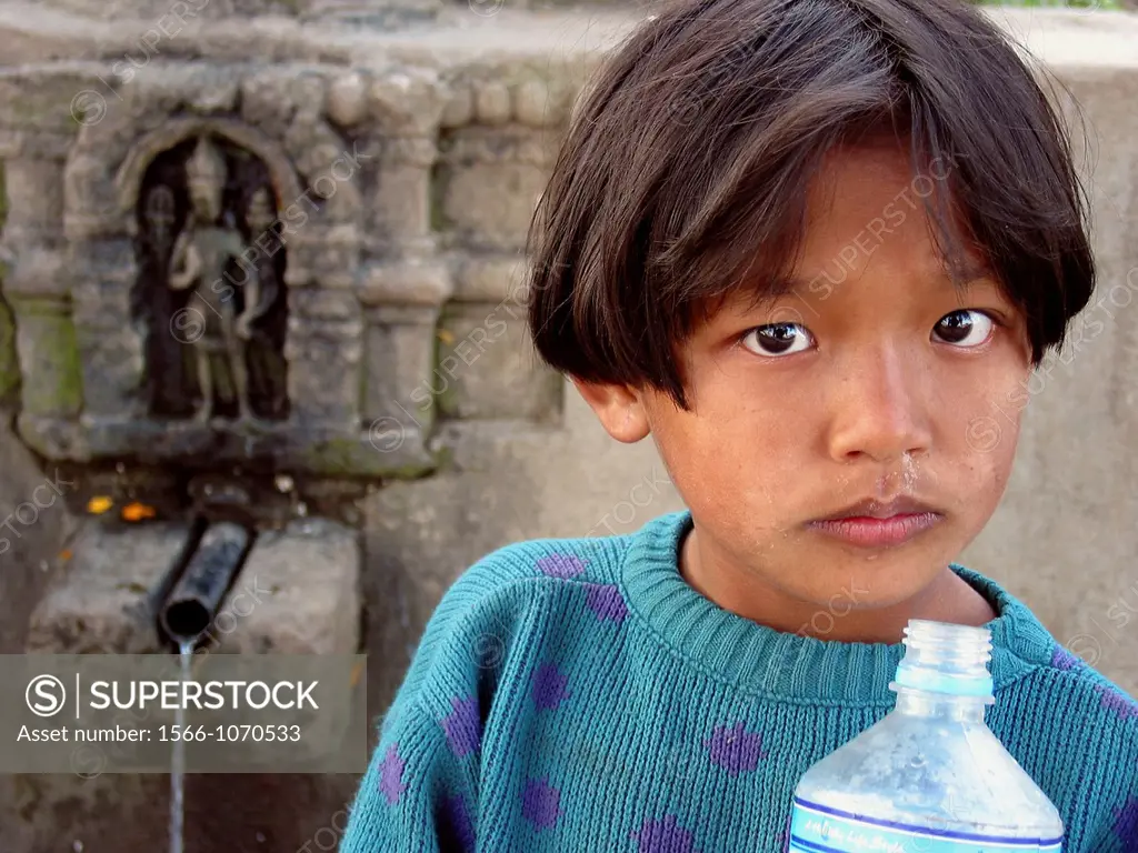 Child is taking water from a natural well in Katmandu