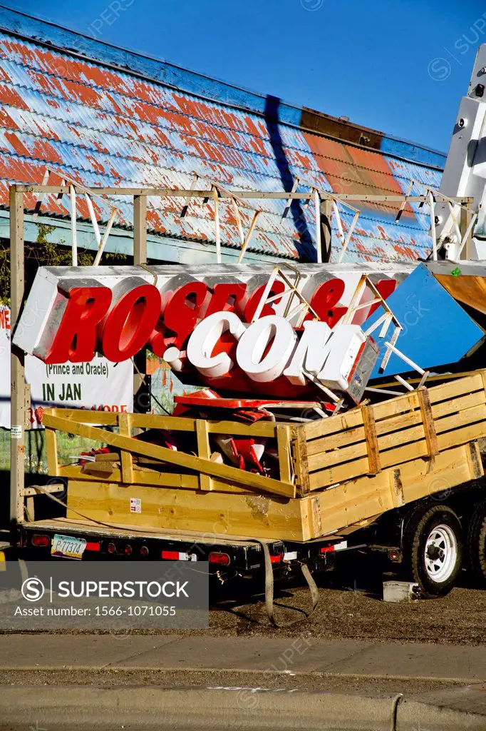 Workmen remove the sign of an unsuccessful dot-com storefront business in Tucson, AZ
