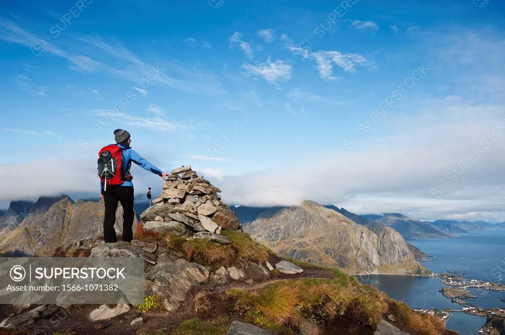 Female hiker enjoys spectacular view over mountains and fjords from Reinebringen, Lofoten islands, Norway