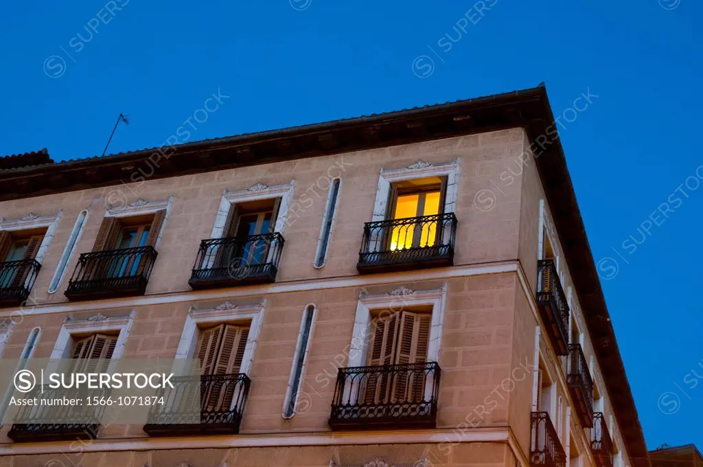 Lit up window in house facade, night view  Isabel II Square, Madrid, Spain 