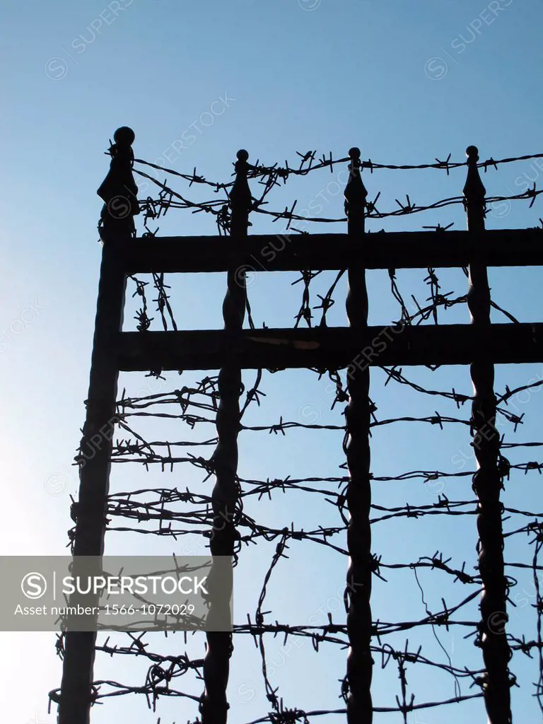 wrought iron fence spikes covered with barbed wire and blue sky
