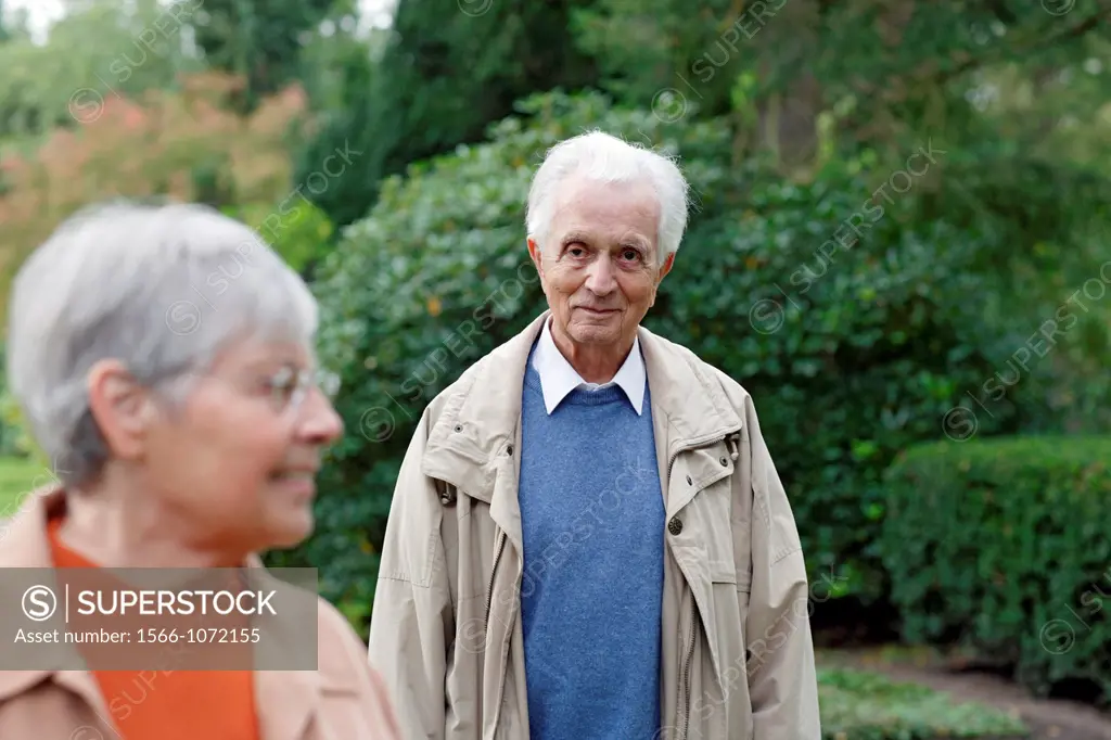 Senior caucasian man looking at senior woman with glasses, blurred green background, Hamburg, Germany, Europe