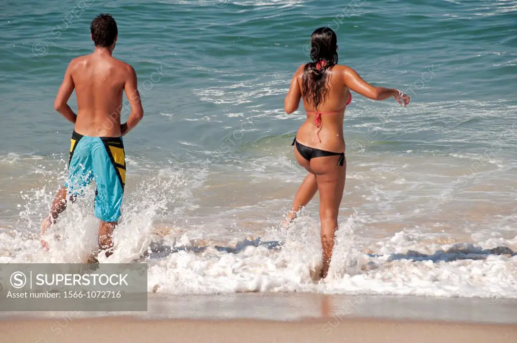 Young couple entering the water on Atlantic Ocean, Portugal, Silver Coast, May