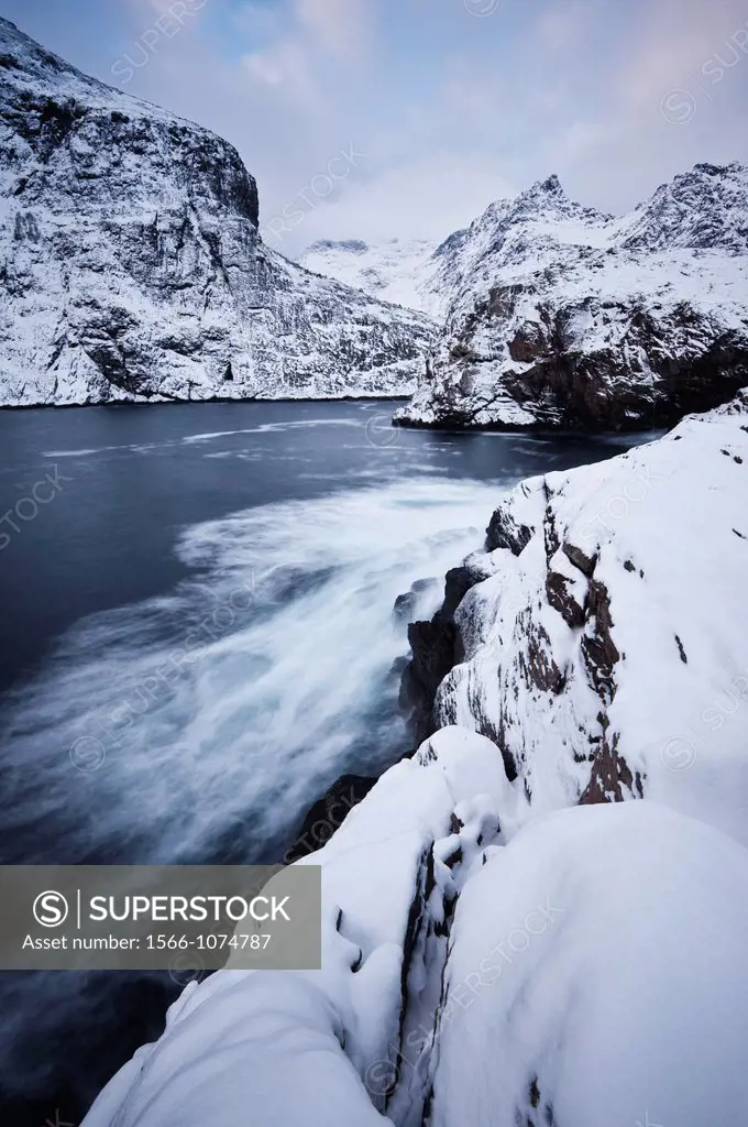 Snow covered cliffs and mountains rise from sea, Lofoten, Lofoten Islands, Norway