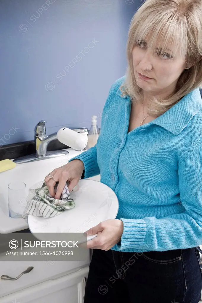 Middle-age woman drying a dish in her kitchen