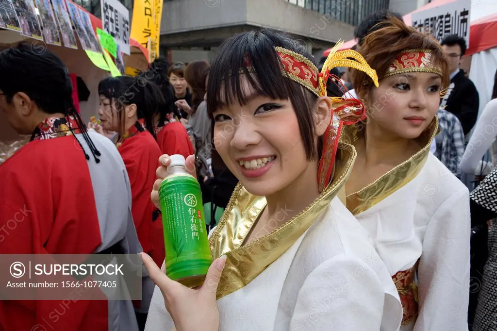 A japanese woman shows her favourite softdrink She is part of a dancegroup which explains her nice dress she is wearing