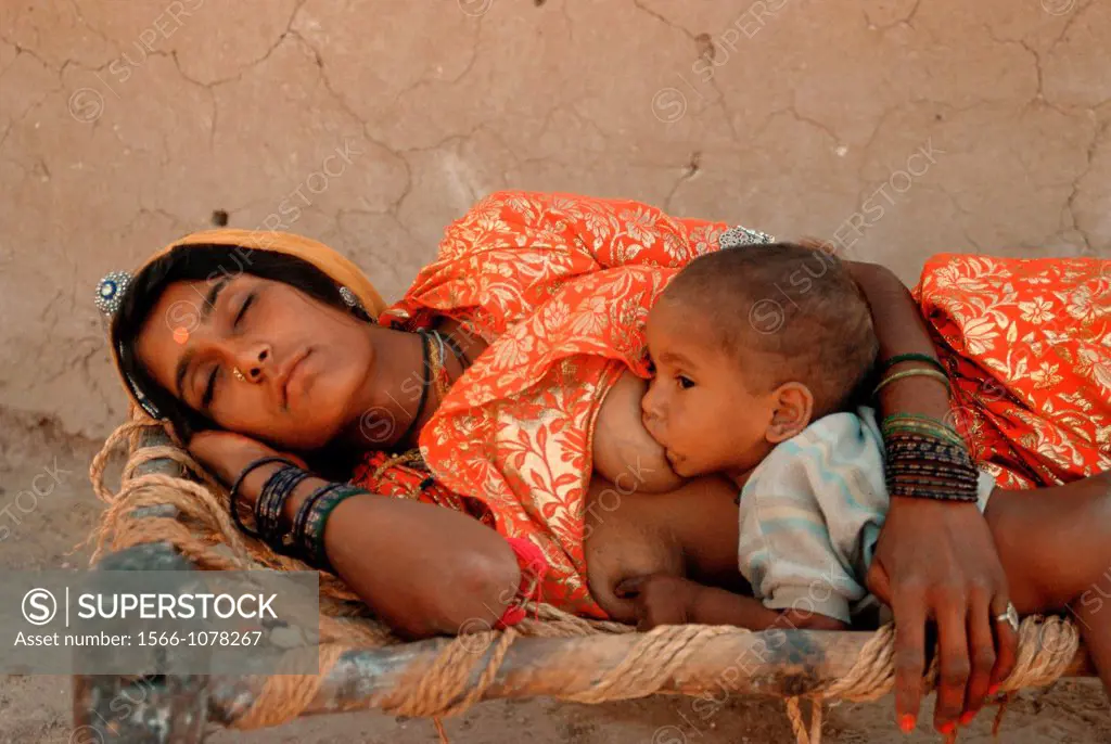 A hindu woman is sleeping while her baby is suckling. From a village in Thar desert, Rajasthan, India.