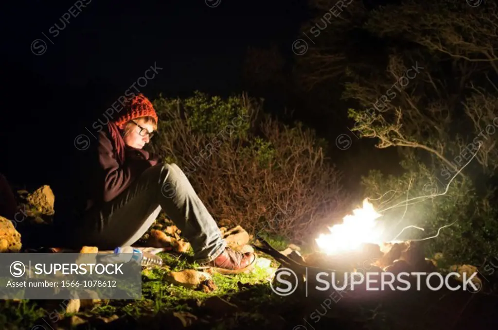 Woman sitting by campfire on Lycian Way trail, near Kas, Antalya Province, Turkey
