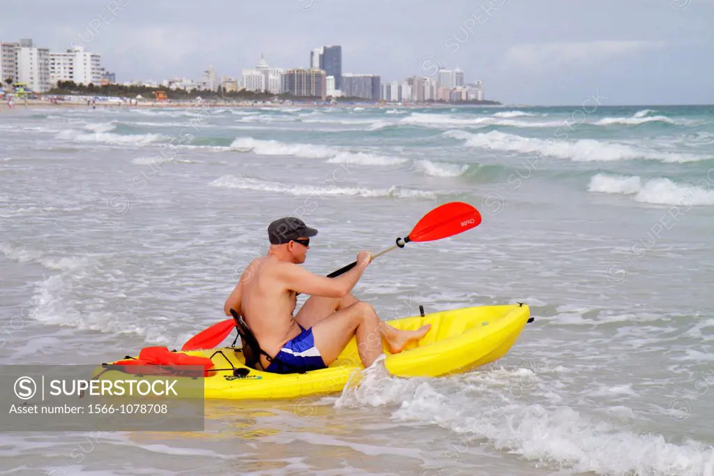 Florida, Miami Beach, Atlantic Ocean, shore, surf, waves, man, bathing suit, yellow polyethylene plastic ocean kayak, dragging, entering water, paddle...