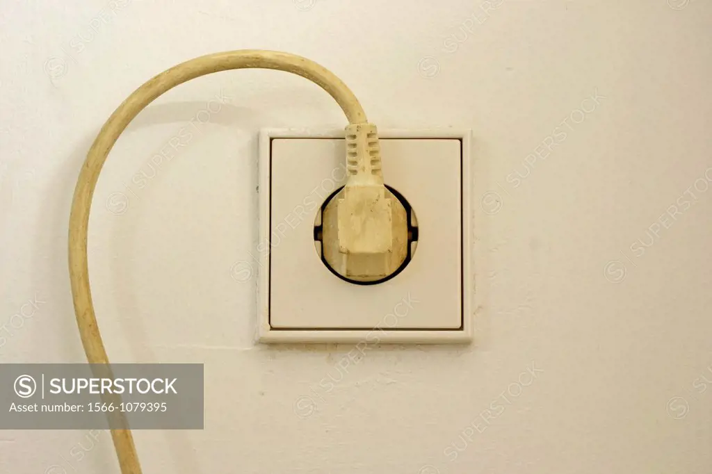 electrical cord plugged into wall socket, cord curving around socket