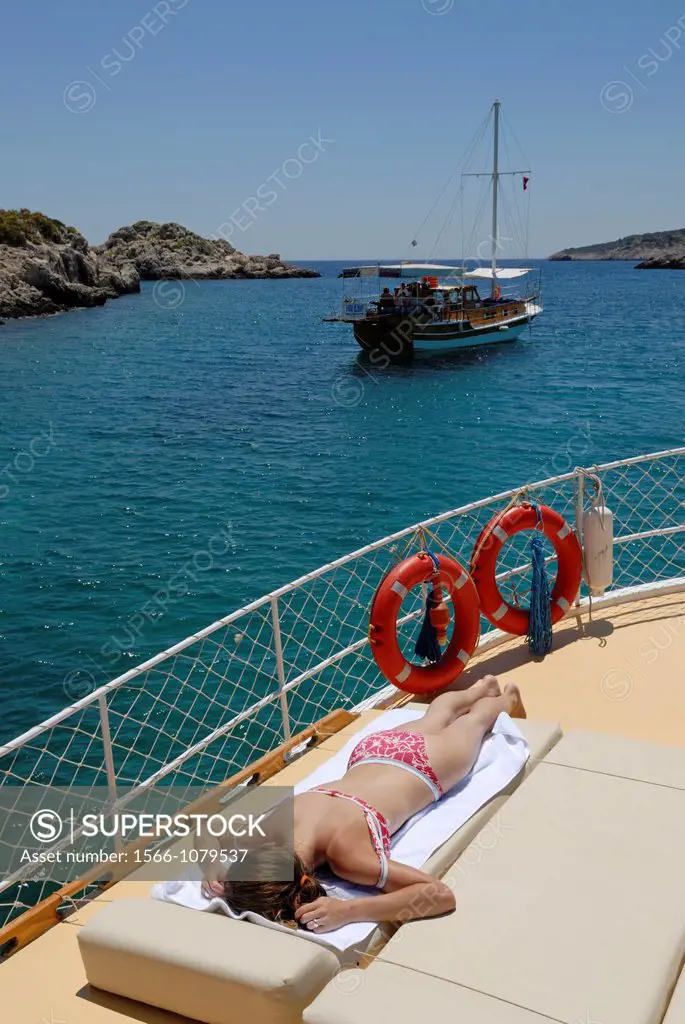 young woman sunbathing on the deck of a schooner, Kekova bay, Turkey, Eurasia