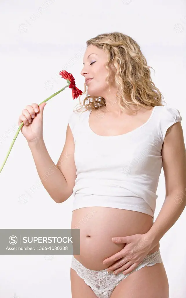 Blonde pregnant woman with flower in studio