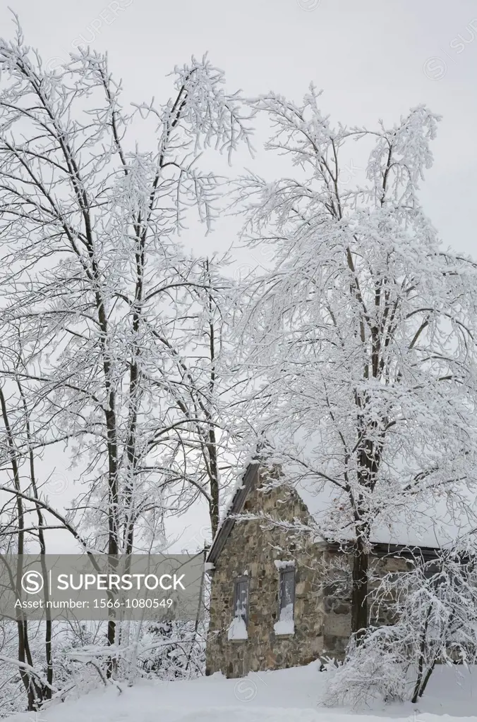 Old Fieldstone constructed Tibitts Hill School House through Snow covered Trees in Winter, Eastern Townships, Quebec