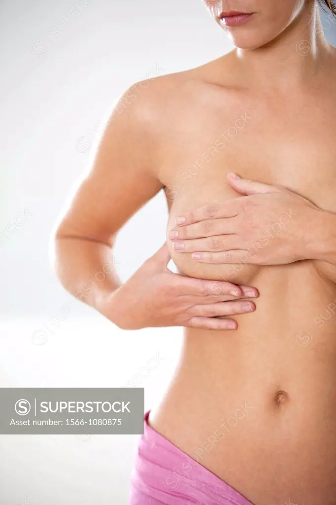 Naked young woman self examining her breasts for cancer