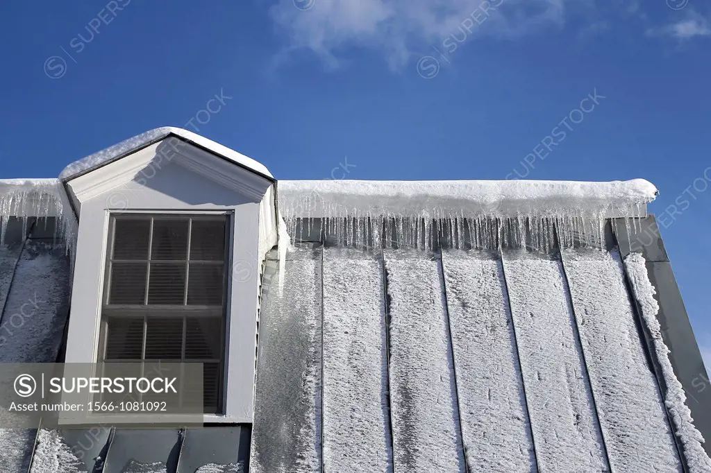 Iclicles hanging over a metal roof on a building in Vermont under a blue sky  Grafton, Vermont, United States