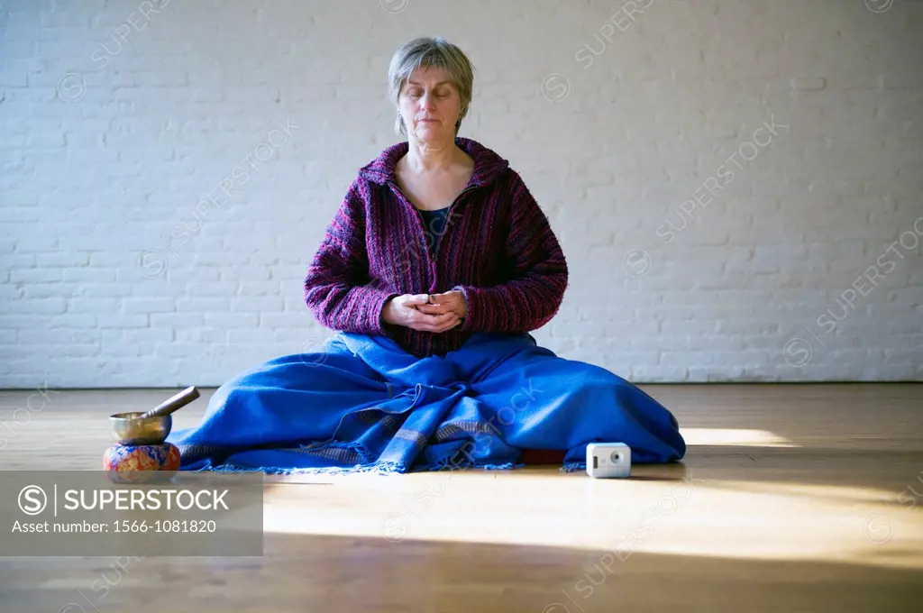 Tilburg, Netherlands. Older woman, meditating in an empty room, using Buddhist techniques.