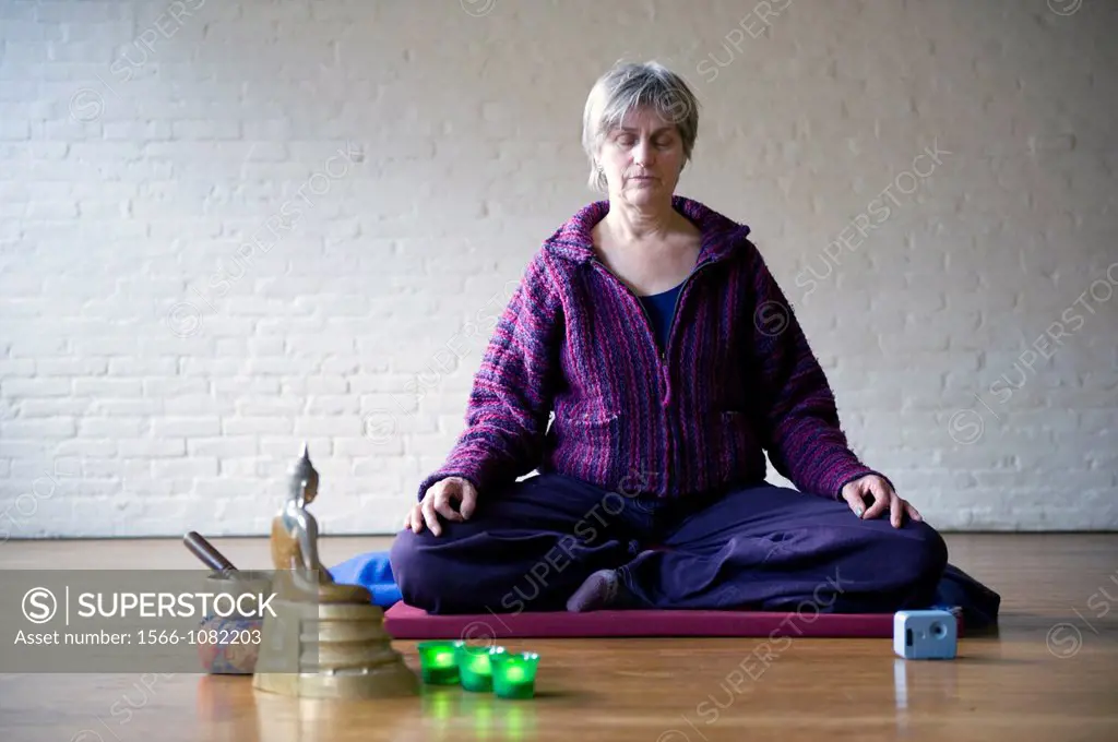 Older woman, meditating in an empty room, using Buddhist techniques.
