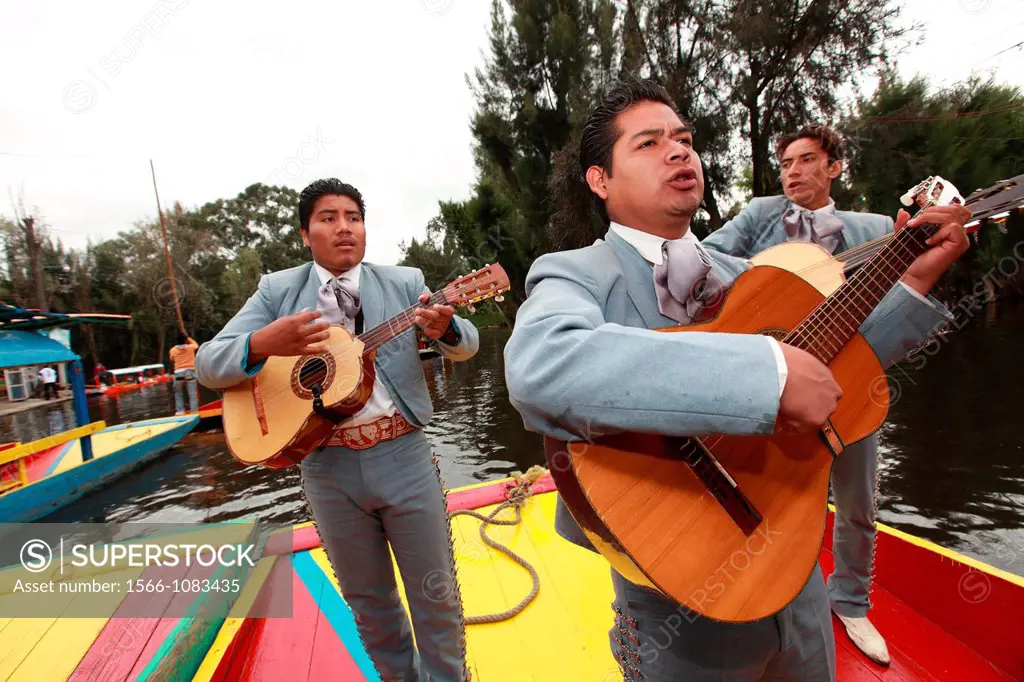 Three Mariachis playing music for tourists on a boat in the canal of Floating Gardens of Xochimilco  Xochimilco  Mexico.