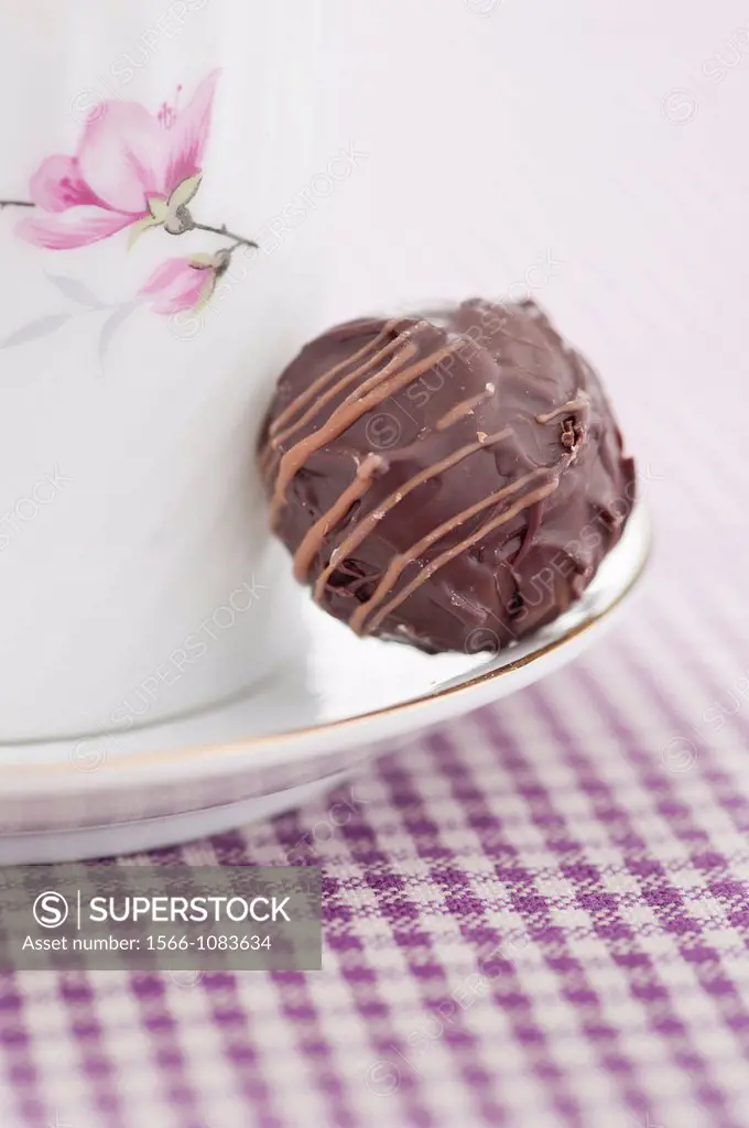 Closeup of a chocolate truffle and a coffee cup