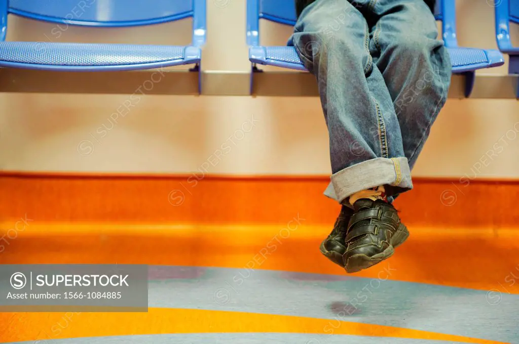 Stock photo of a boys legs swinging from a chair