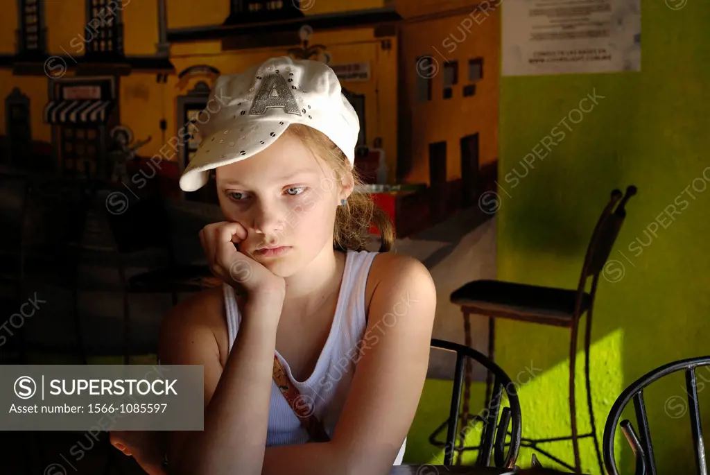 Young girl with hat wating for fod at a restaurant, Nogales, Mexico