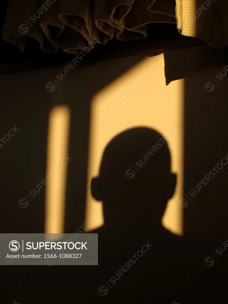 Man´s head shadow on room wall with curtains
