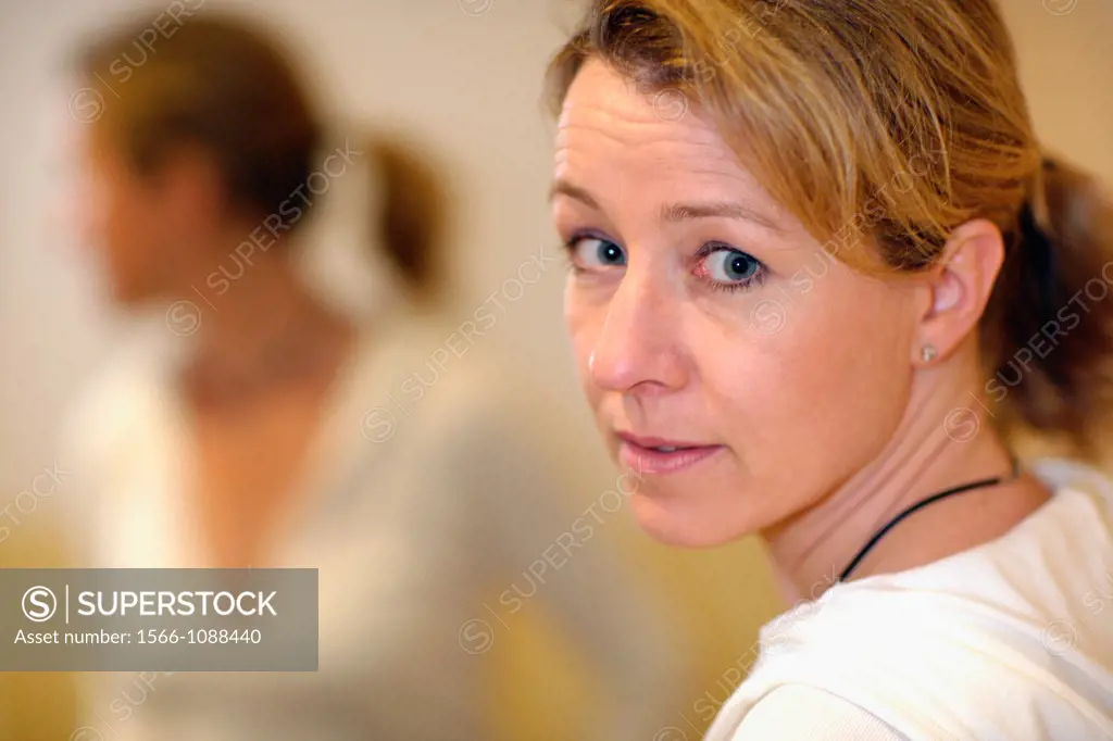 Yong caucasian woman with long blond hair looking back over her shoulder, surprised, with her blurred image in the mirror, Hamburg, Germany, Europe