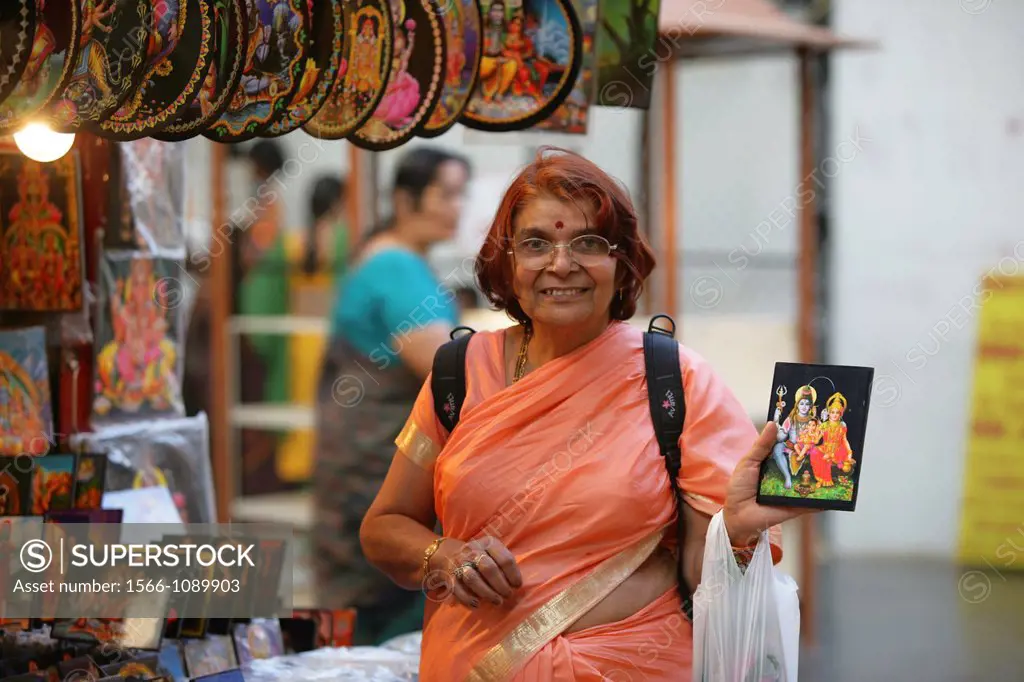 Elderly Hindu woman smiling and showing a picture of Gods Shiva and Parvati in Bangalore, India