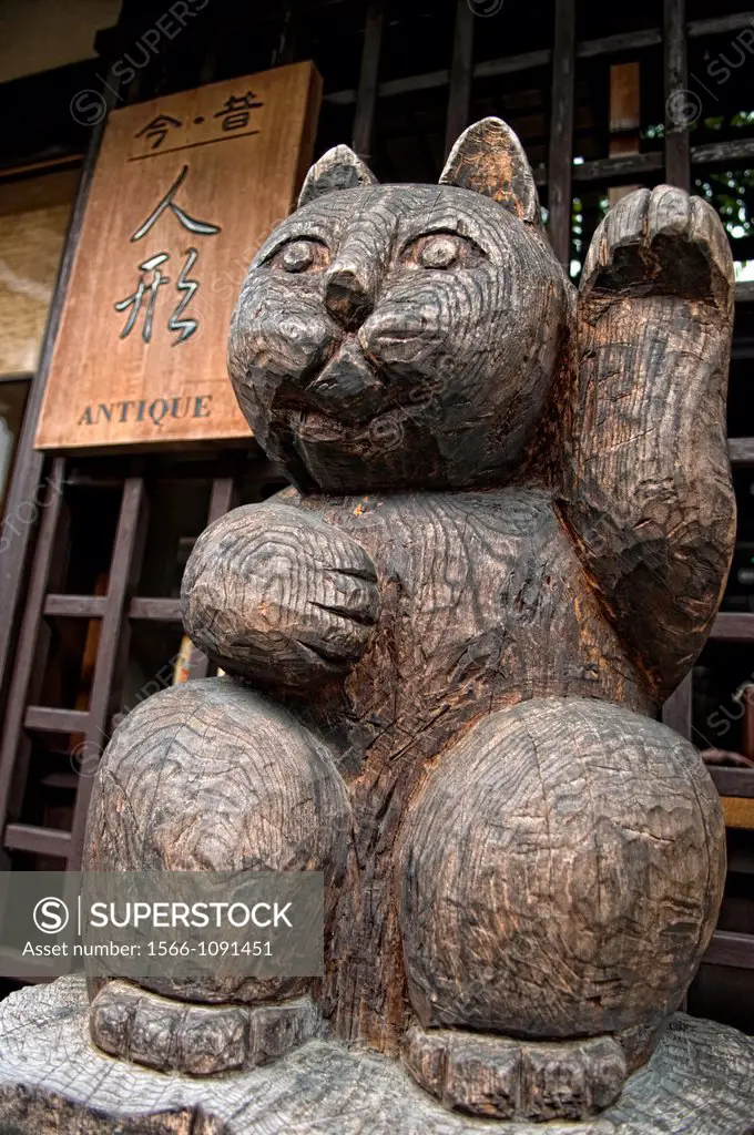 A carved wooden lucky cat maneki neko in front of an antique store in Takayama Japan