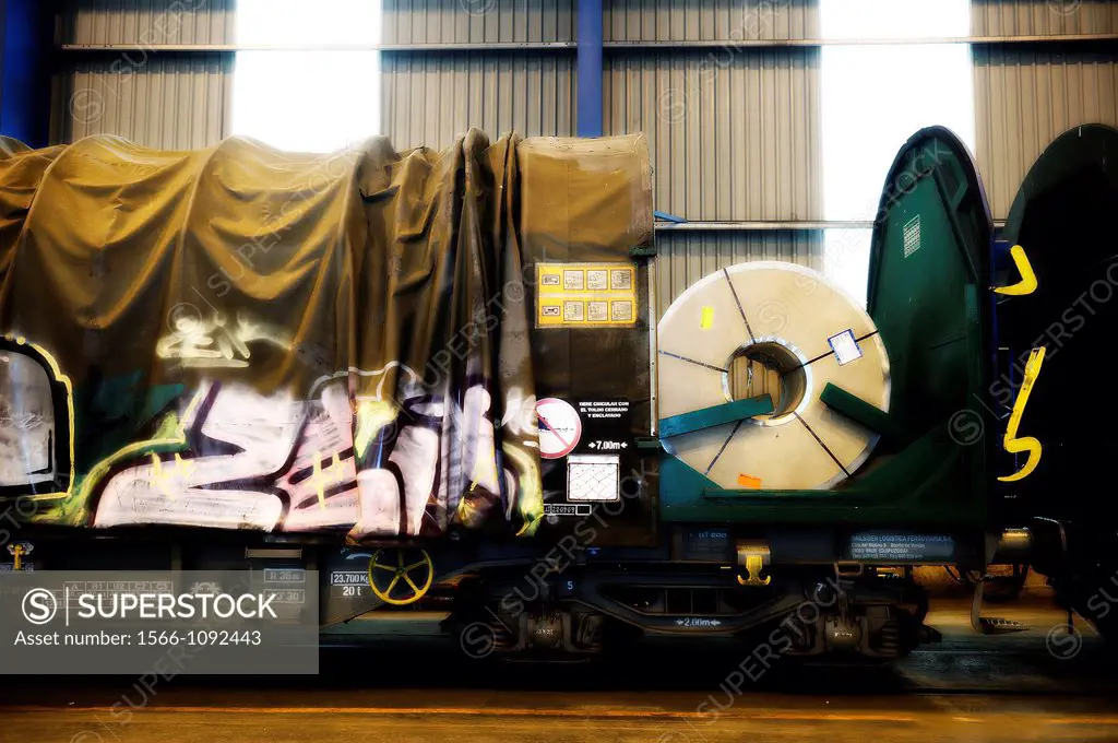 Graffiti on a train car with a steel coil loaded inside