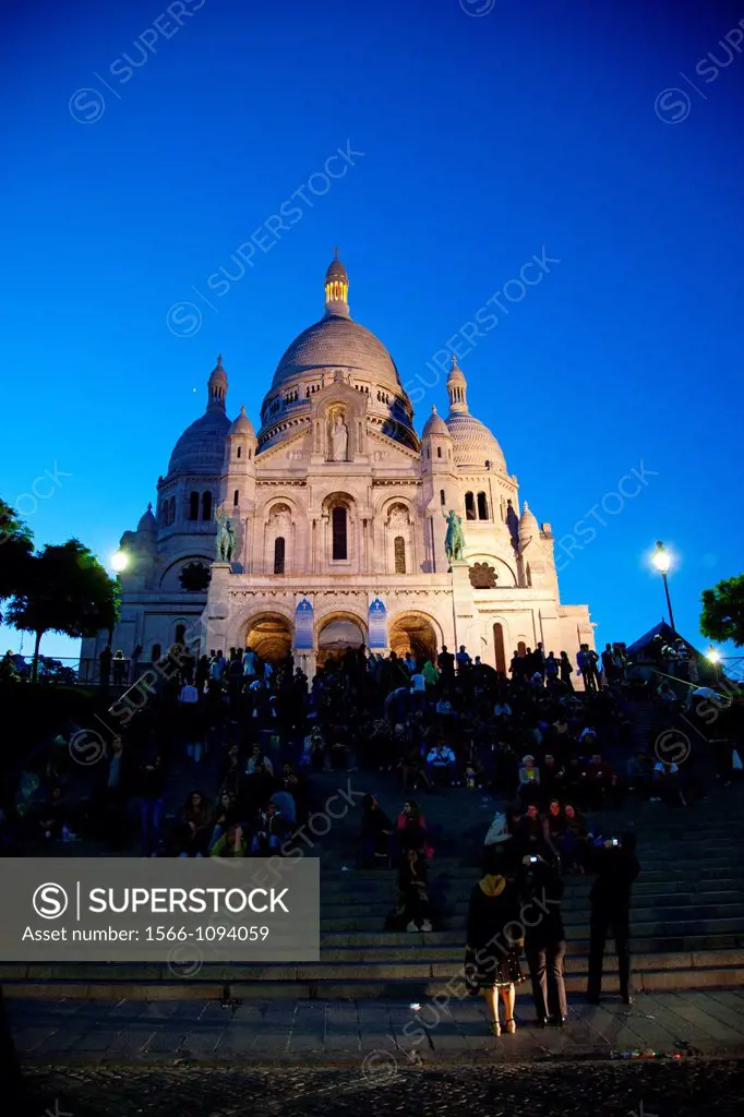 Visitors gather outside the Sacre Coeur Basilica at night in Paris, France