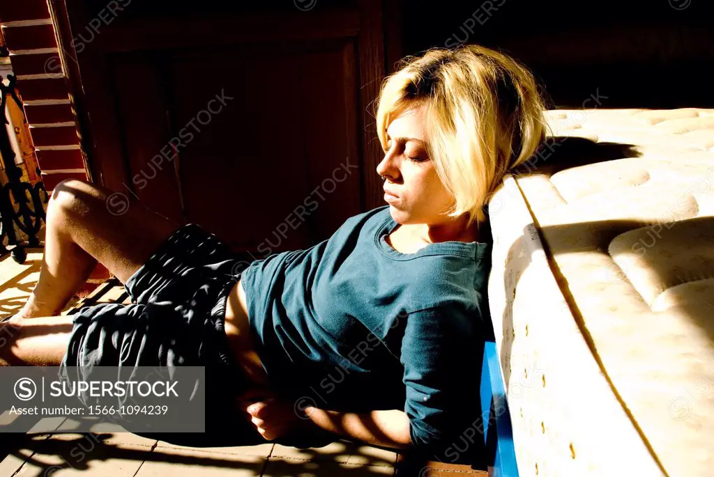 Photograph of a girl lying in the floor with the sun in her face.