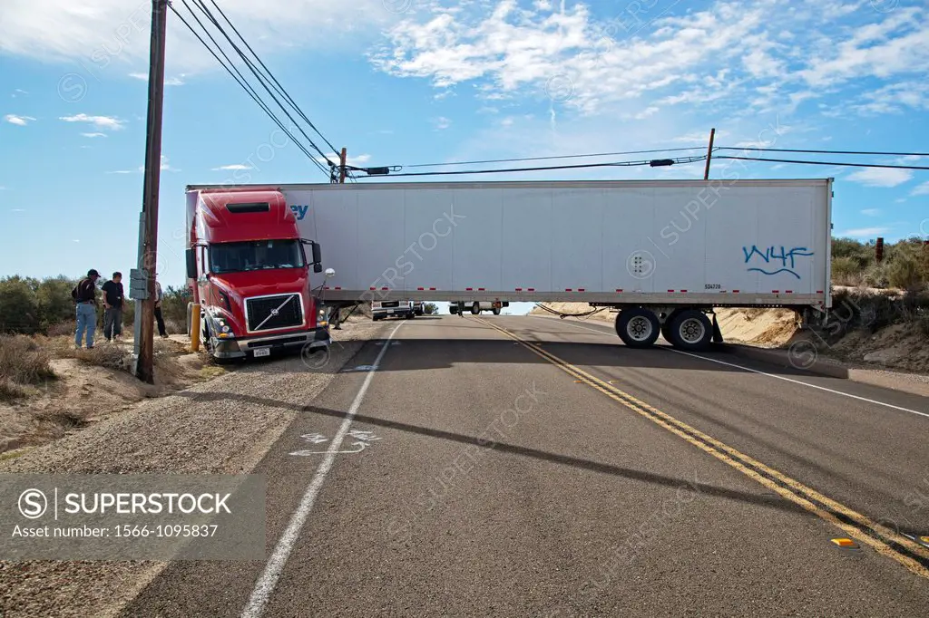 Campo, California - A tractor-trailer is stuck in soft sand and wedged between utility equipment, blocking traffic on California Highway 94, after the...