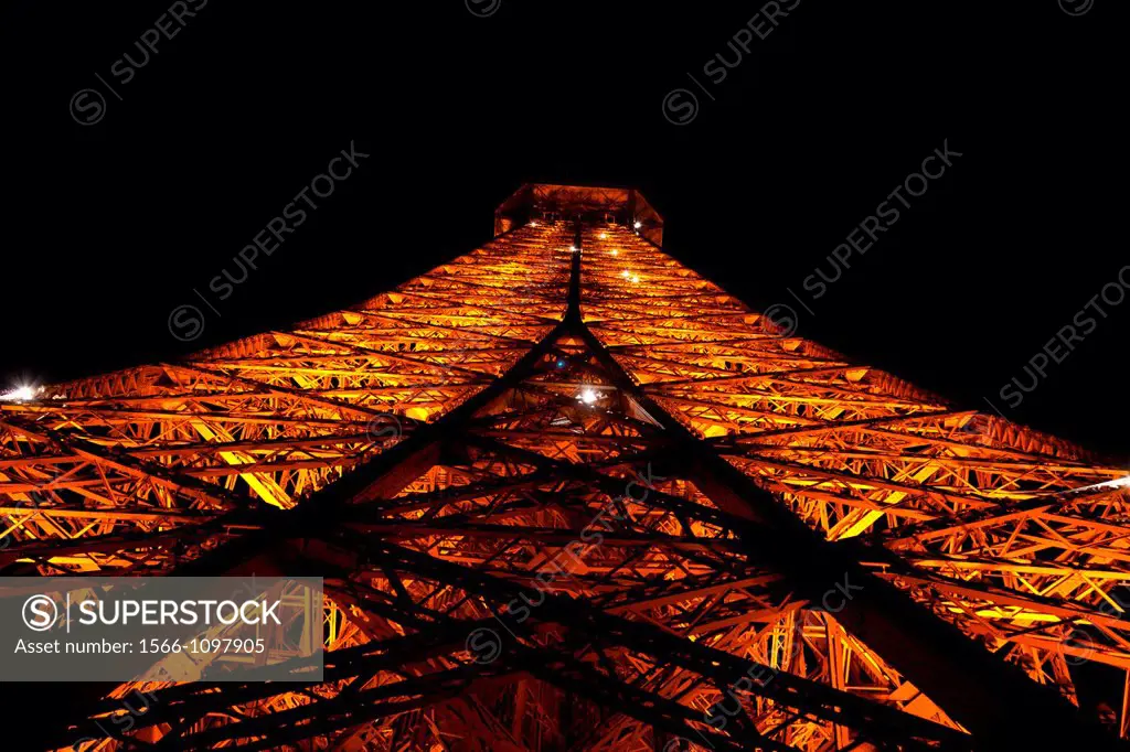 Looking up at the spire of the Eiffel Tower in Paris at night, France