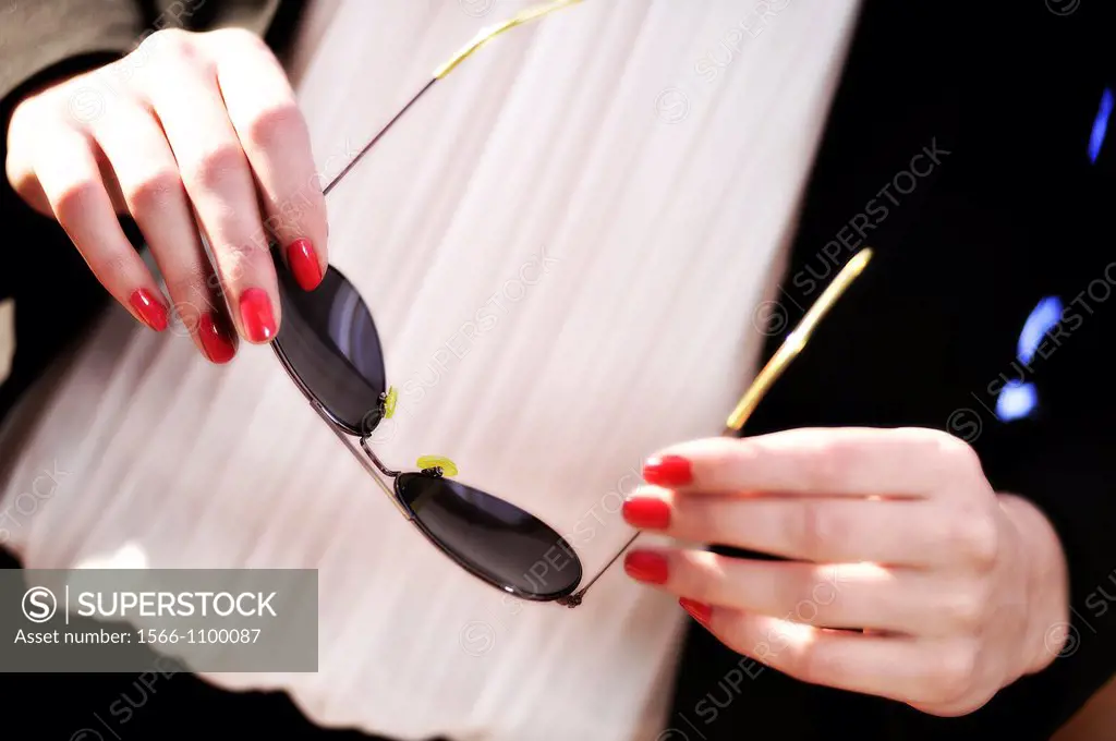 Hands of young woman holding a pair of sunglasses