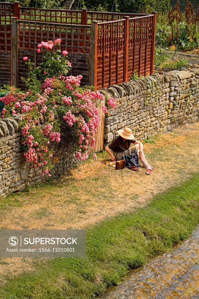 Woman in straw hat having picnic by canal in tourist town of Helmsley England