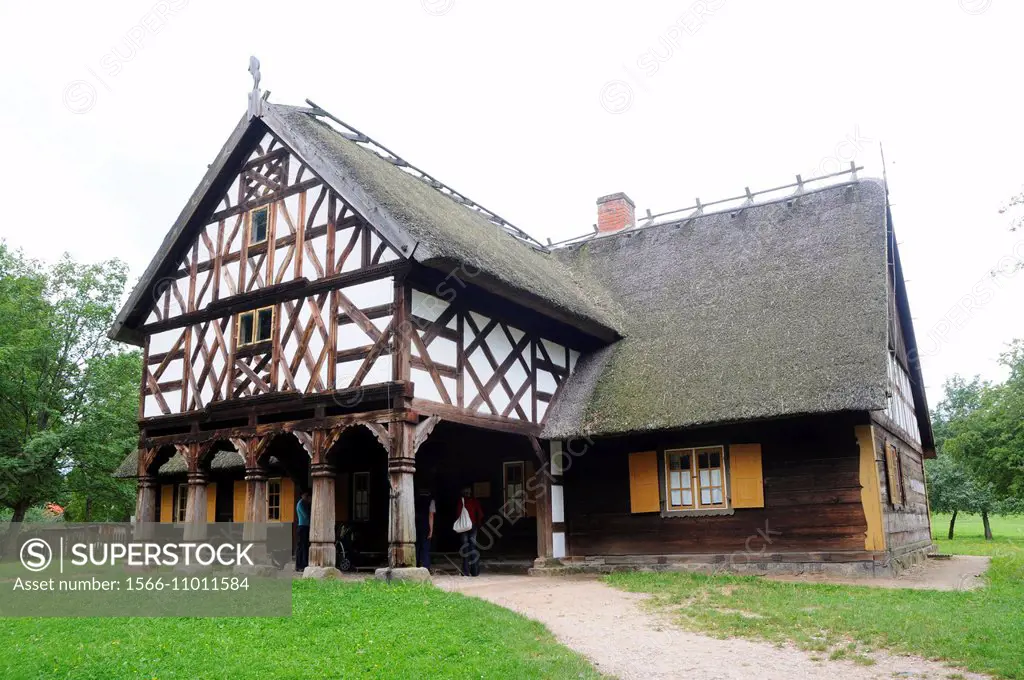 Replica of early 20th century hut with arcade extension, partly half-timbered wall and thatched roof from Masuria region, Poland.