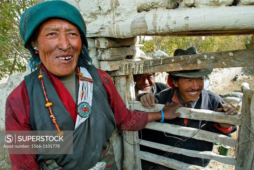Woman with green head scarf and man in trilby at gate in village Tibet