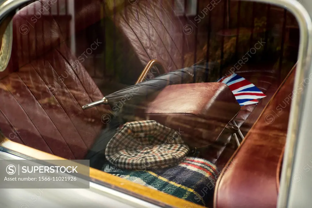 Foreground inside an antique car brand Rover with red leather upholstery with two umbrelas, hat, car blanquet and an english flag in England, UK, Euro...