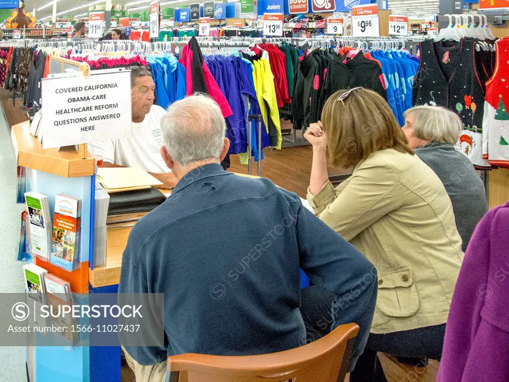 An insurance agent advises customers at a sales kiosk at a Laguna Niguel, CA, discount clothing store offering coverage under the Affordable Healthcar...