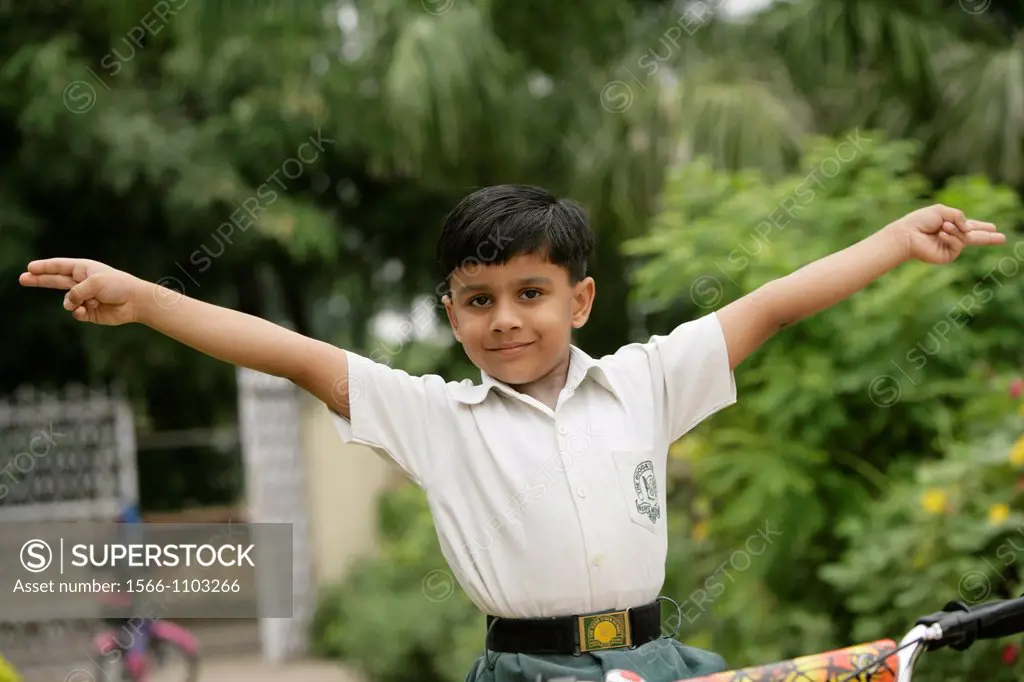 Young Indian school boy expressing elation with arms raised as if he is flying.