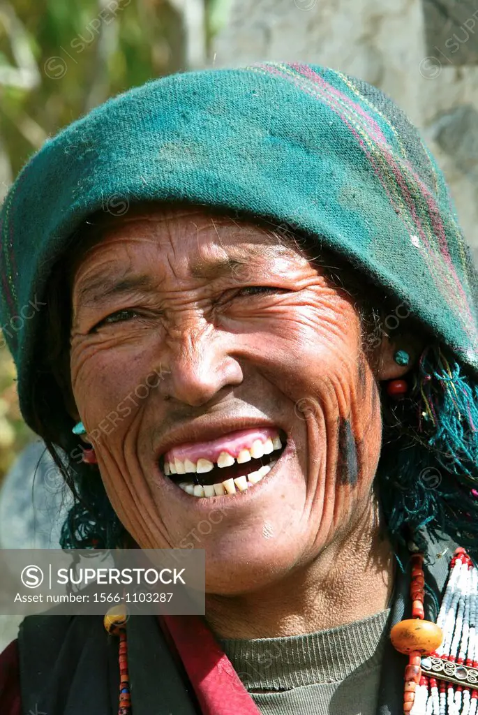 Older woman with green head scarf laughs village Tibet