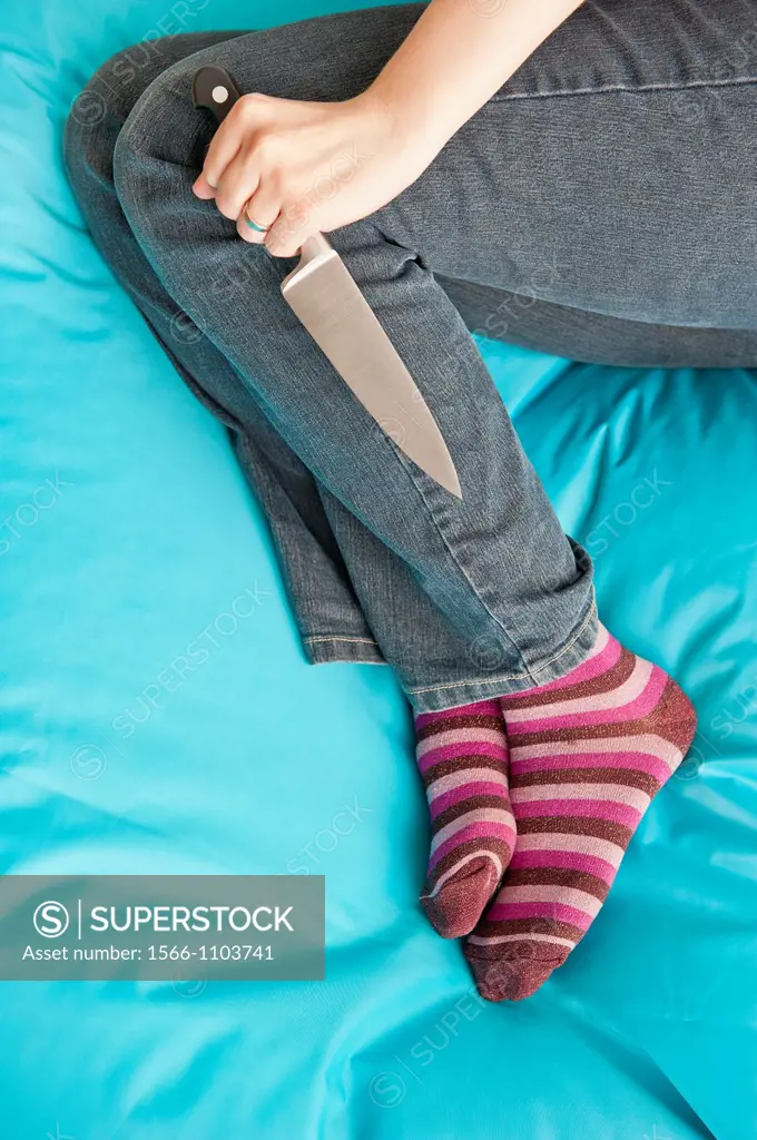 Woman lying down and holding a knife in a firm grip