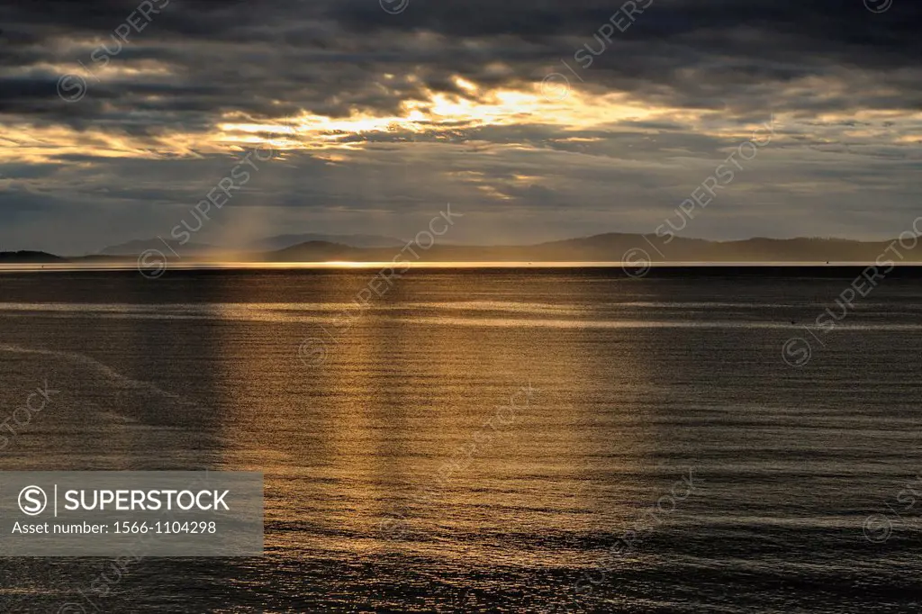Morning clouds over the San Juan Islands with light glinting on Haro Strait, Victoria Cordova Bay, BC, Canada