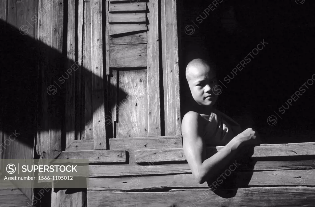 Young Buddhist monk at the window of a wooden monastery in Bagan