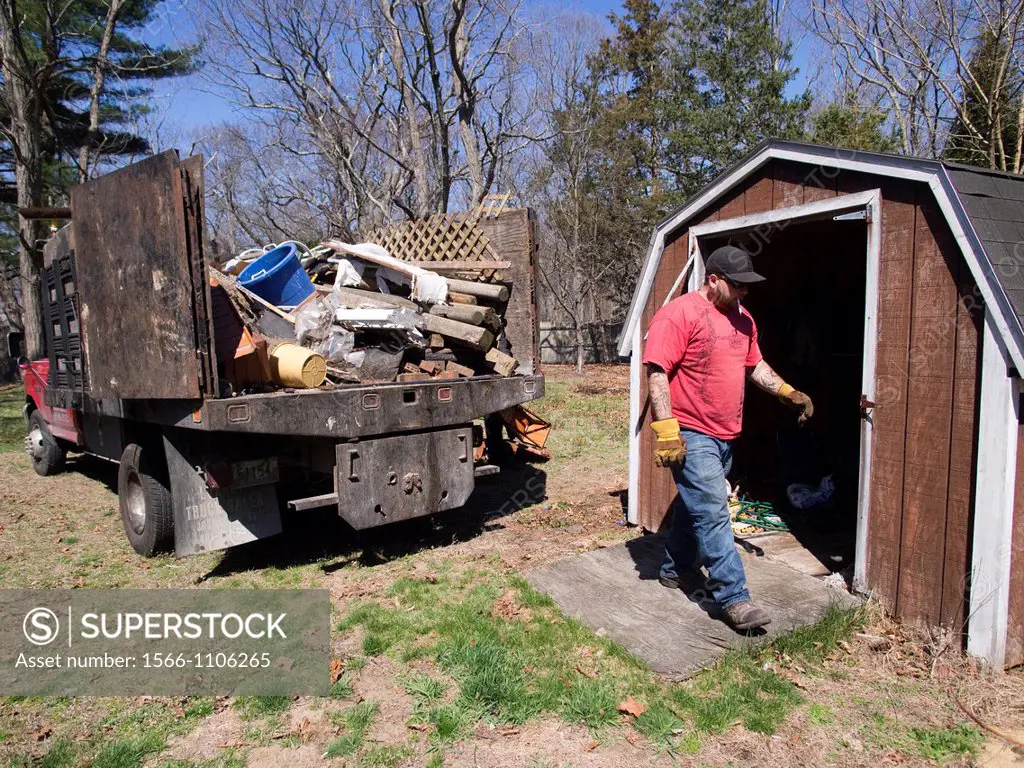 Worker cleaning out backyard of foreclosed home outside of a foreclosed home in Warwick, Rhode Island
