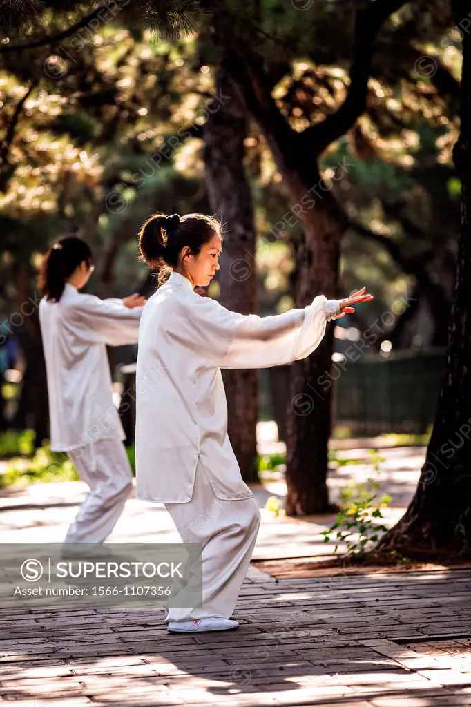 Chinese people practices tai chi martial arts exercise early morning at the Temple of Heaven Park during summer in Beijing, China