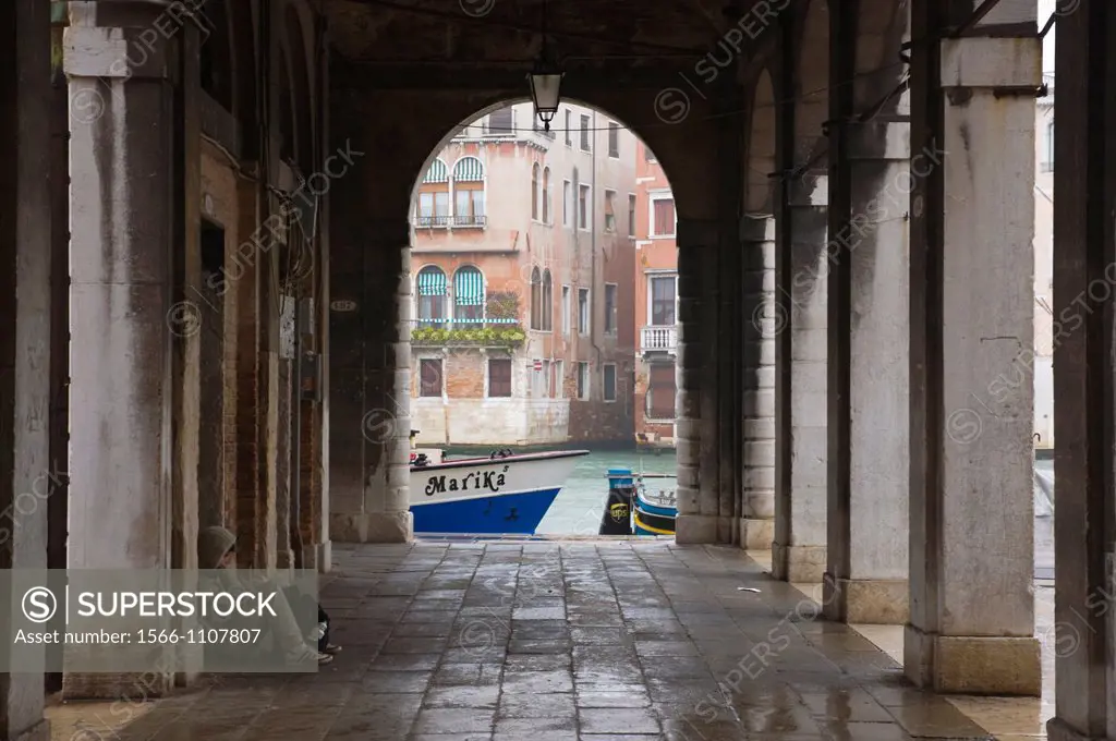 Person reading by Grand Canal in vaulted passages around Campo San Giovanni di Rialto square Venice northern Italy Europe