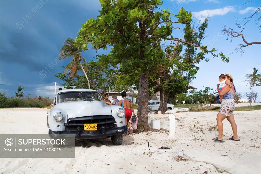 Cuban family around their old American car at Playa Ancon near Trinidad, Cuba
