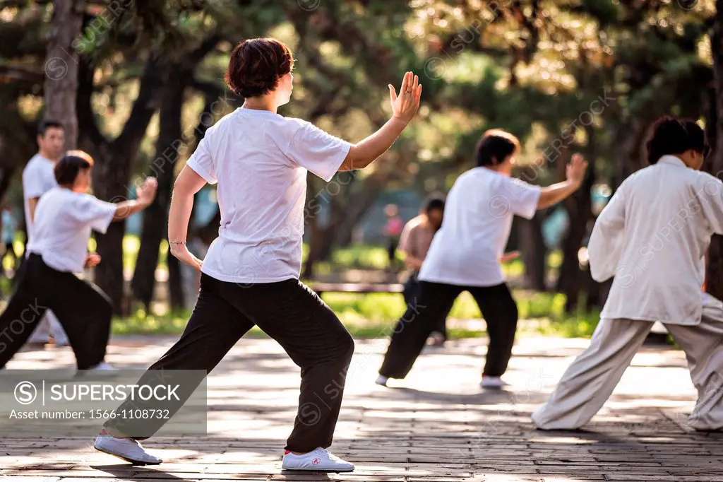 Chinese people practices tai chi martial arts exercise early morning at the Temple of Heaven Park during summer in Beijing, China